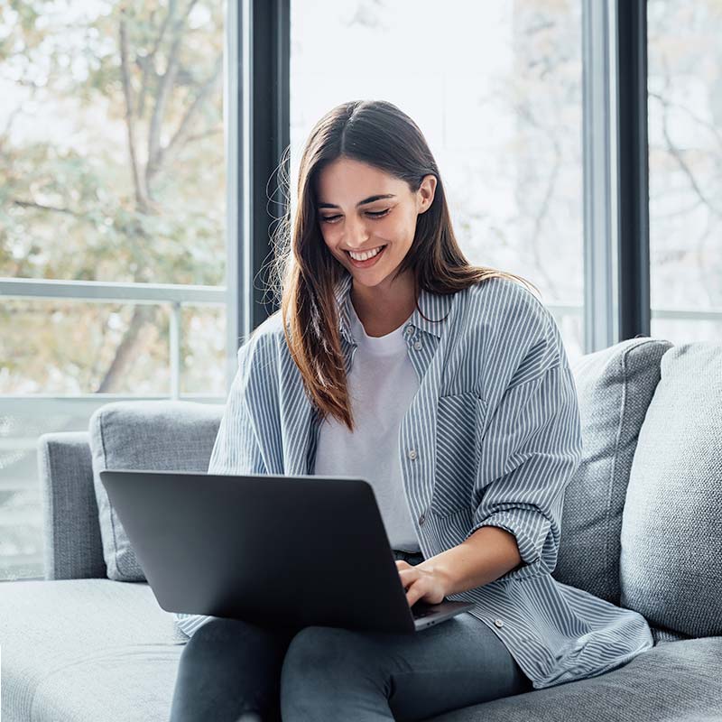 Mujer usando una computadora portátil junto a la ventana