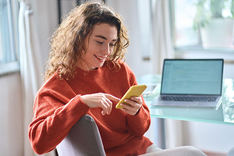 Woman-using-yellow-cell-phone-and-laptop