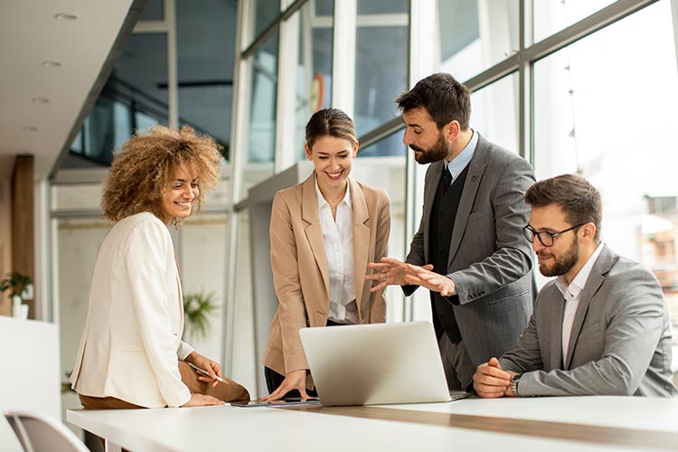 Office workers collaborating around a laptop