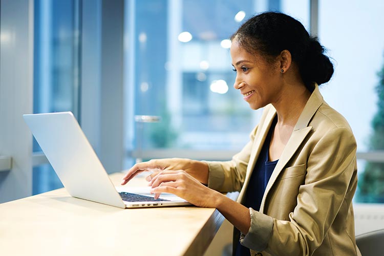 Woman-standing-laptop-workjpg Man and woman looking at laptop while at the office